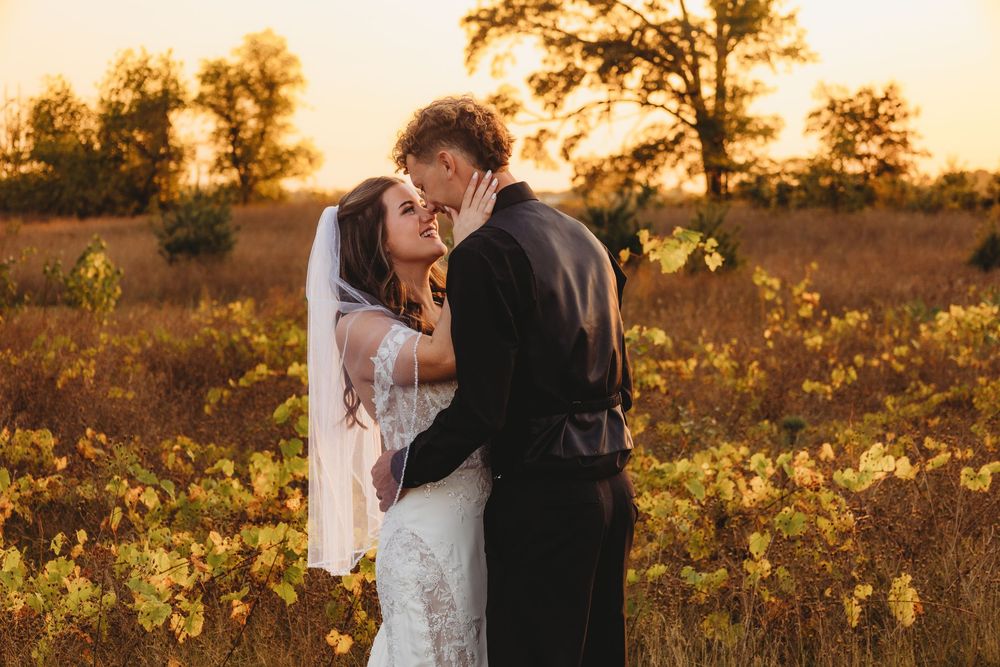 A couple shares a romantic embrace during golden hour in a wildflower field at sunset.
