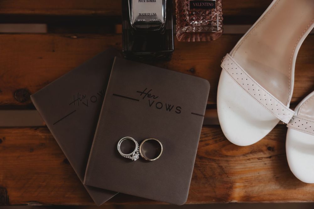 Wedding shoes and rings arranged on rustic wooden surface with elegant packaging and decor.