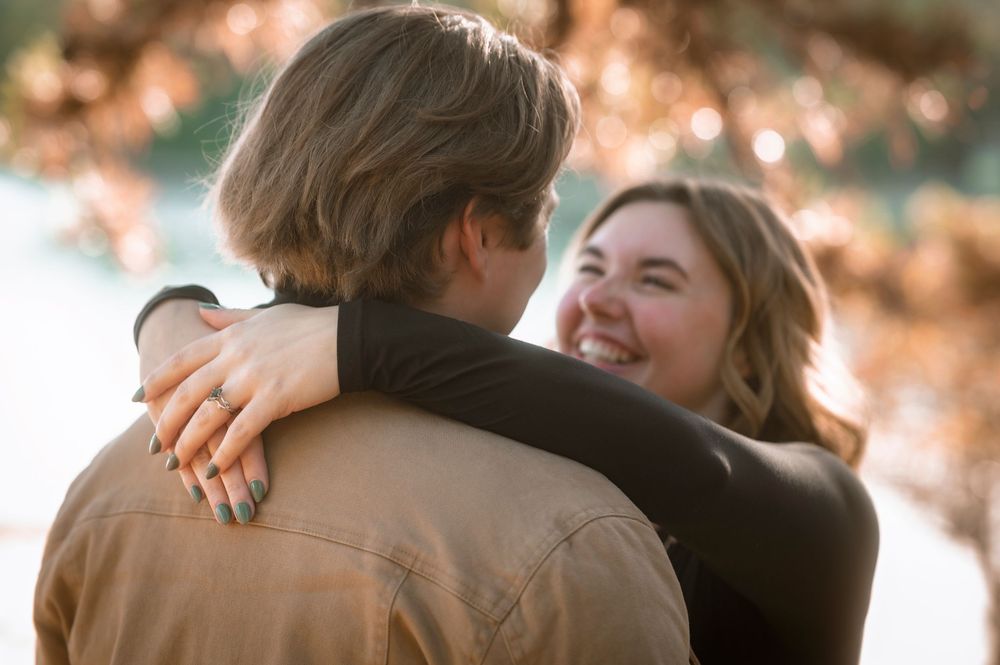 A couple shares a romantic embrace in an outdoor setting with warm autumn lighting.