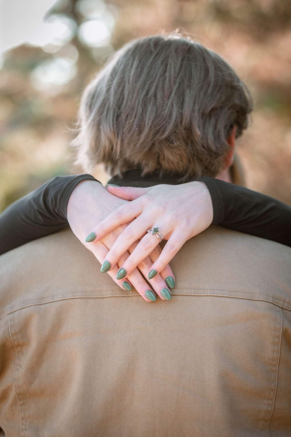 Close up shots showing hands with teal nail polish resting on a brown jacket.