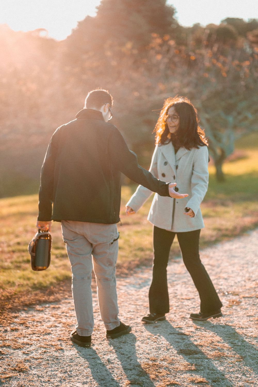 Couple walking together on path during sunset with long shadows.