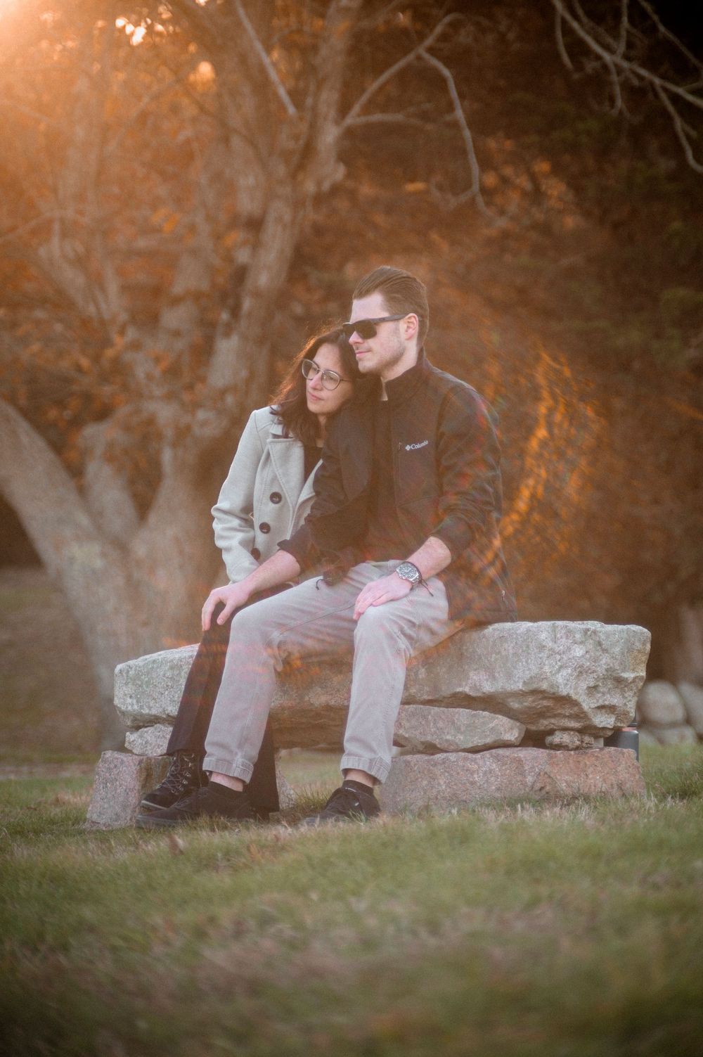 Intimate moment shared on stone bench during golden hour.
