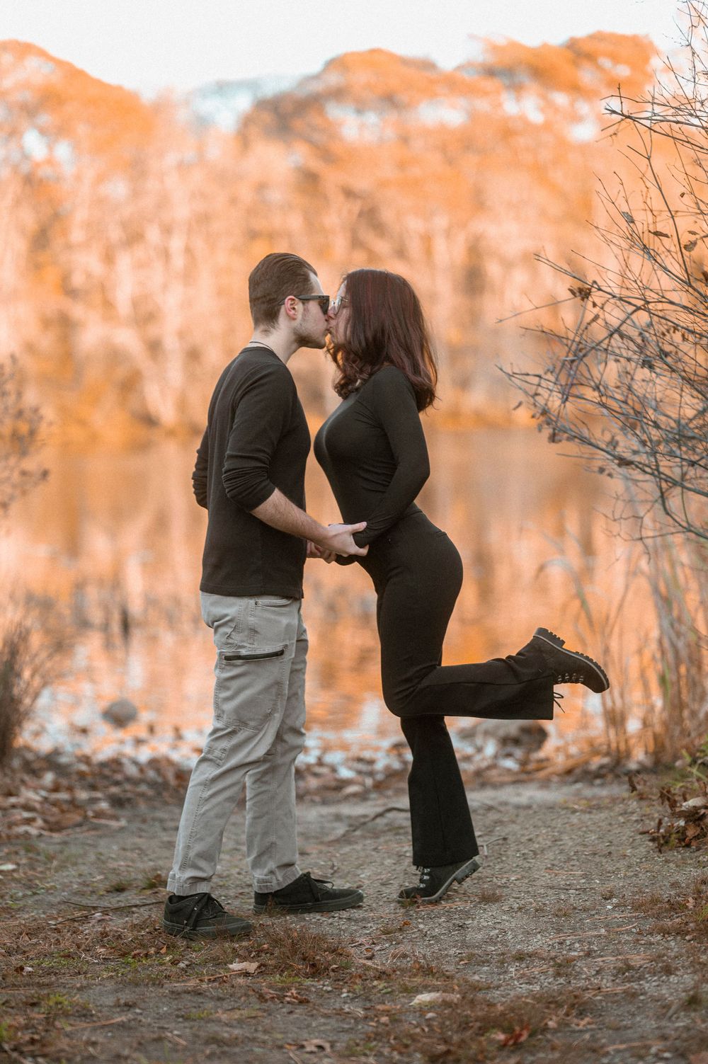 Romantic kiss captured against autumn foliage backdrop.