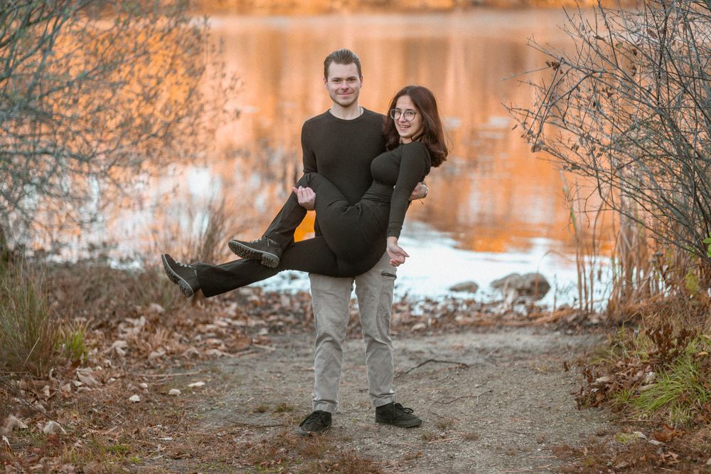 Playful couple moment captured by lake during sunset.