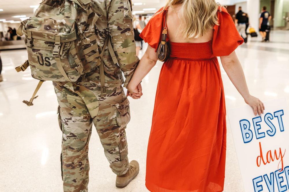 Military service member reunites with loved one wearing bright orange dress in airport New Haven, CT.