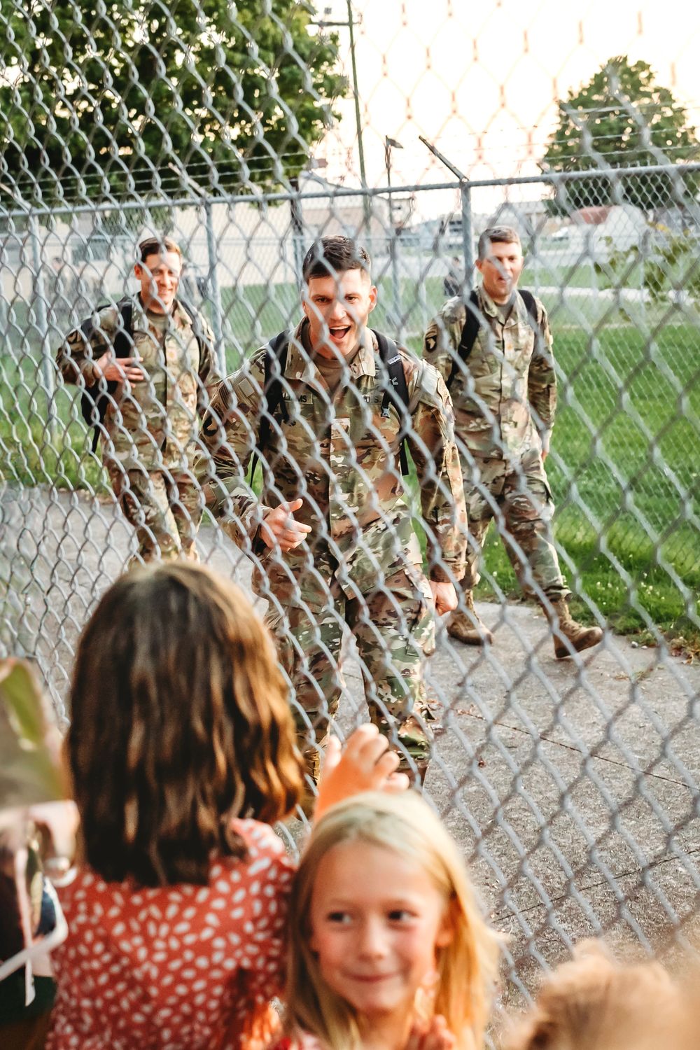Children in polka dot dress watching through chain link fence outdoors in Hamden, CT.