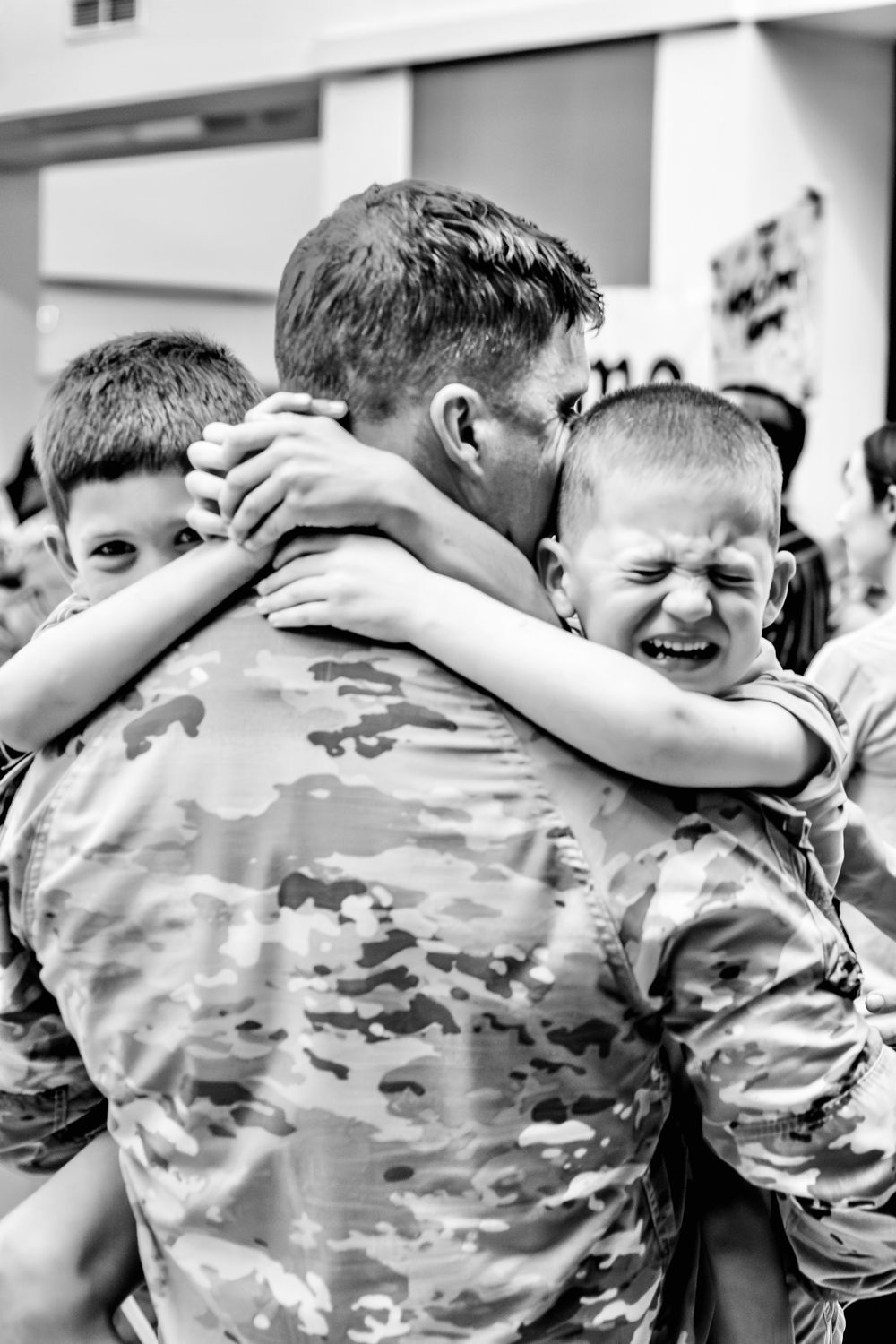 Children in camouflage uniforms sharing joyful group hugs and smiles in North Haven, CT.