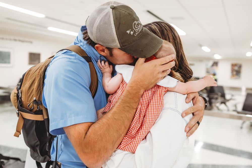 Emotional reunion embrace in bright airport terminal with welcome signs visible in Hamden, CT.
