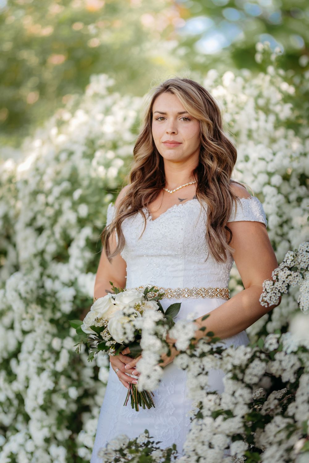 A bridal portrait session in a blooming white flower garden showcasing an elegant lace wedding dress.
