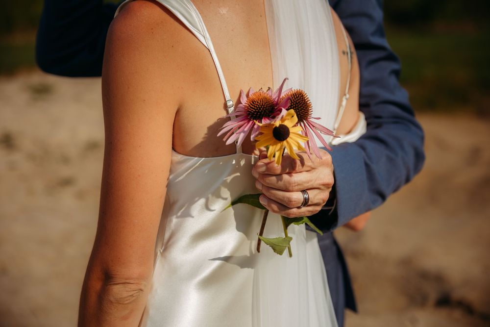 A romantic embrace between a couple in wedding attire with sunlight filtering through autumn trees.