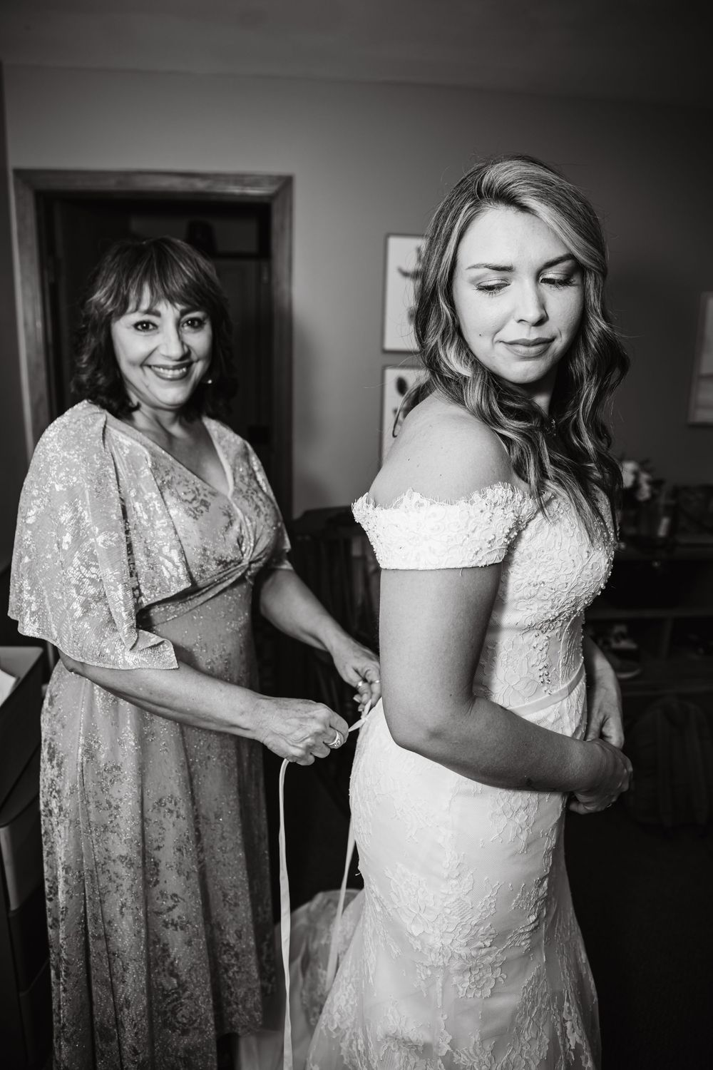 A sequence of black and white photos showing someone getting dressed in a white lace wedding gown.