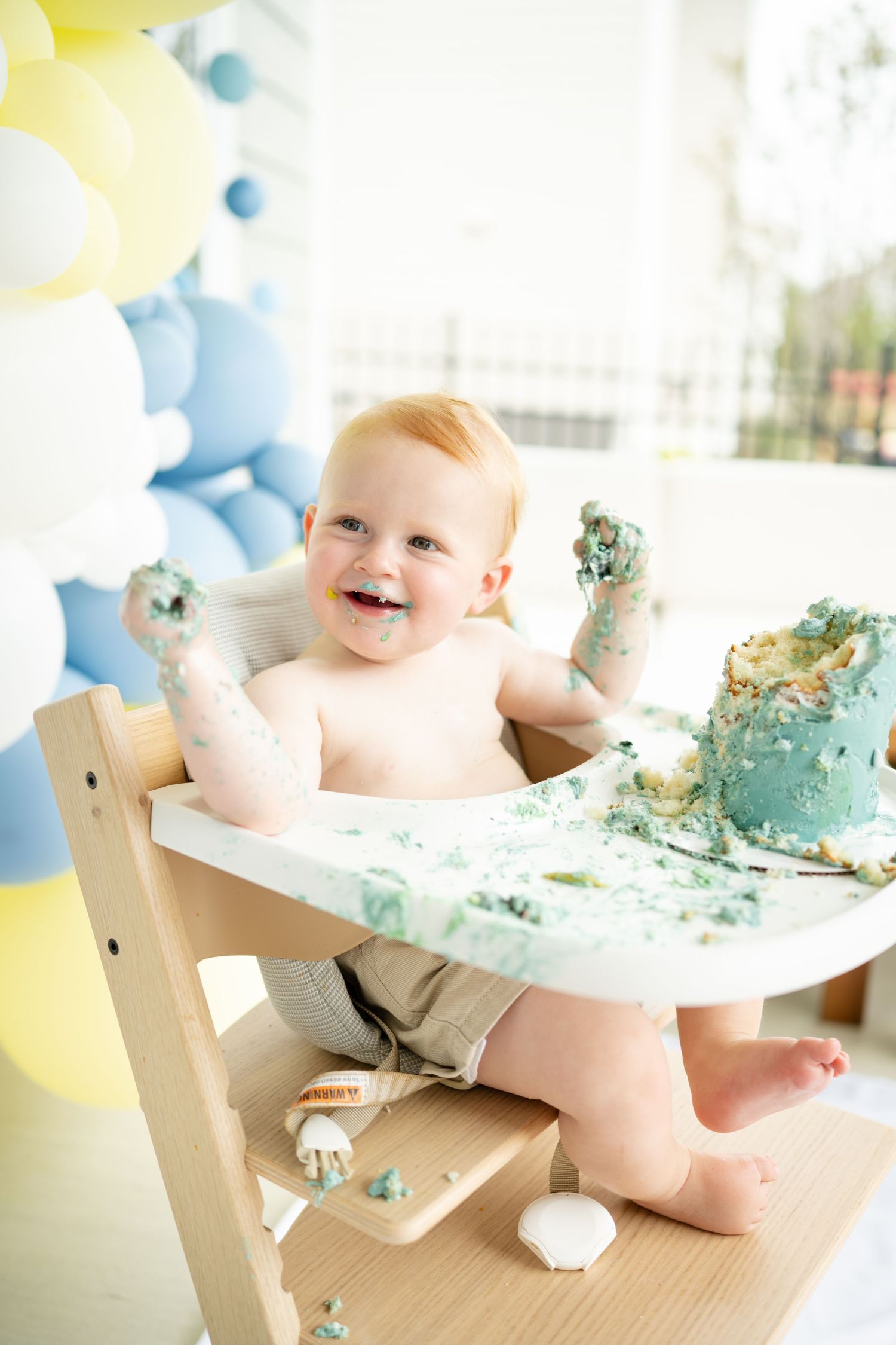 noblesville family photographer, baby girl looks interested in giraffe topper of cake smash cake, all white