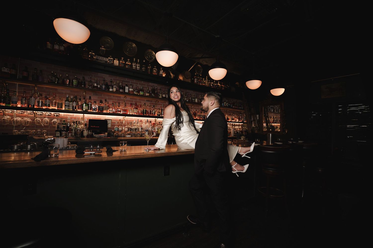 A romantic wedding scene in a dimly lit bar with glowing overhead lights.