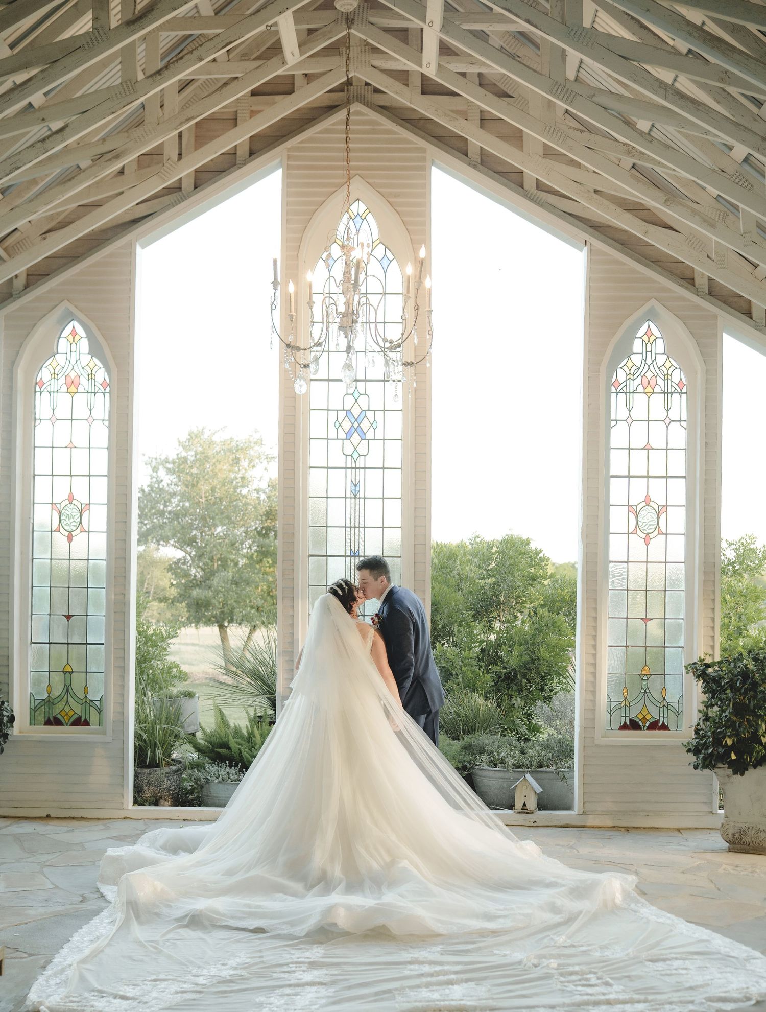 A romantic wedding ceremony in a chapel with stained glass windows and vaulted ceiling.