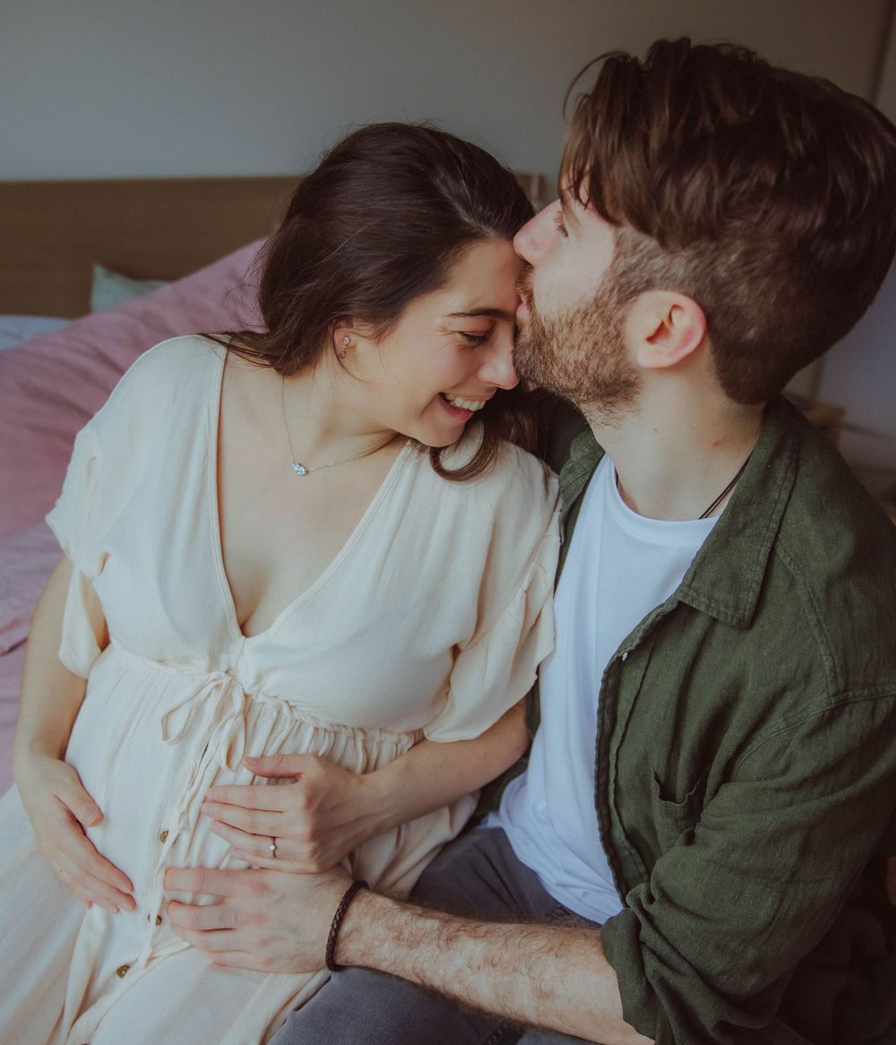 Romantic couple shares an intimate moment as they lean in close together while sitting on a bed.