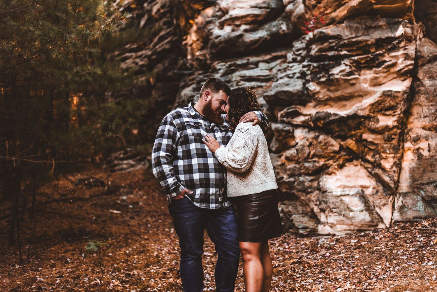 A couple sharing an intimate moment against a rocky cliff face.