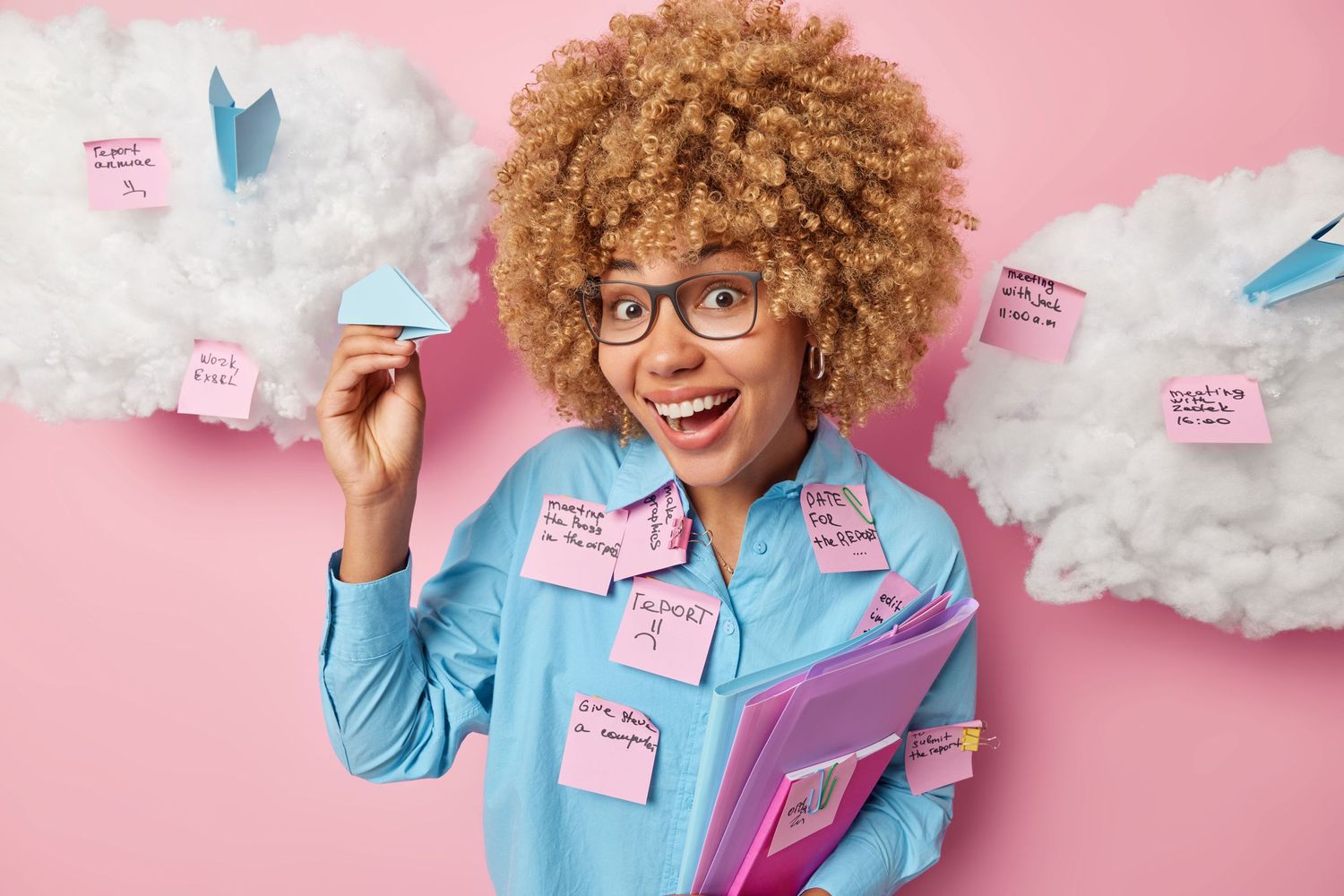 Impressed cheerful office worker holds paper plane folders under arm uses stickers for writing down notes things to do l