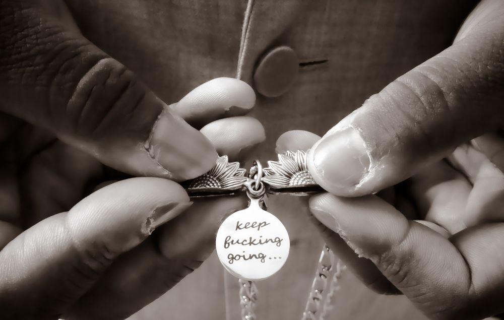 Black and white detail shot of hands holding a small engraved pendant.