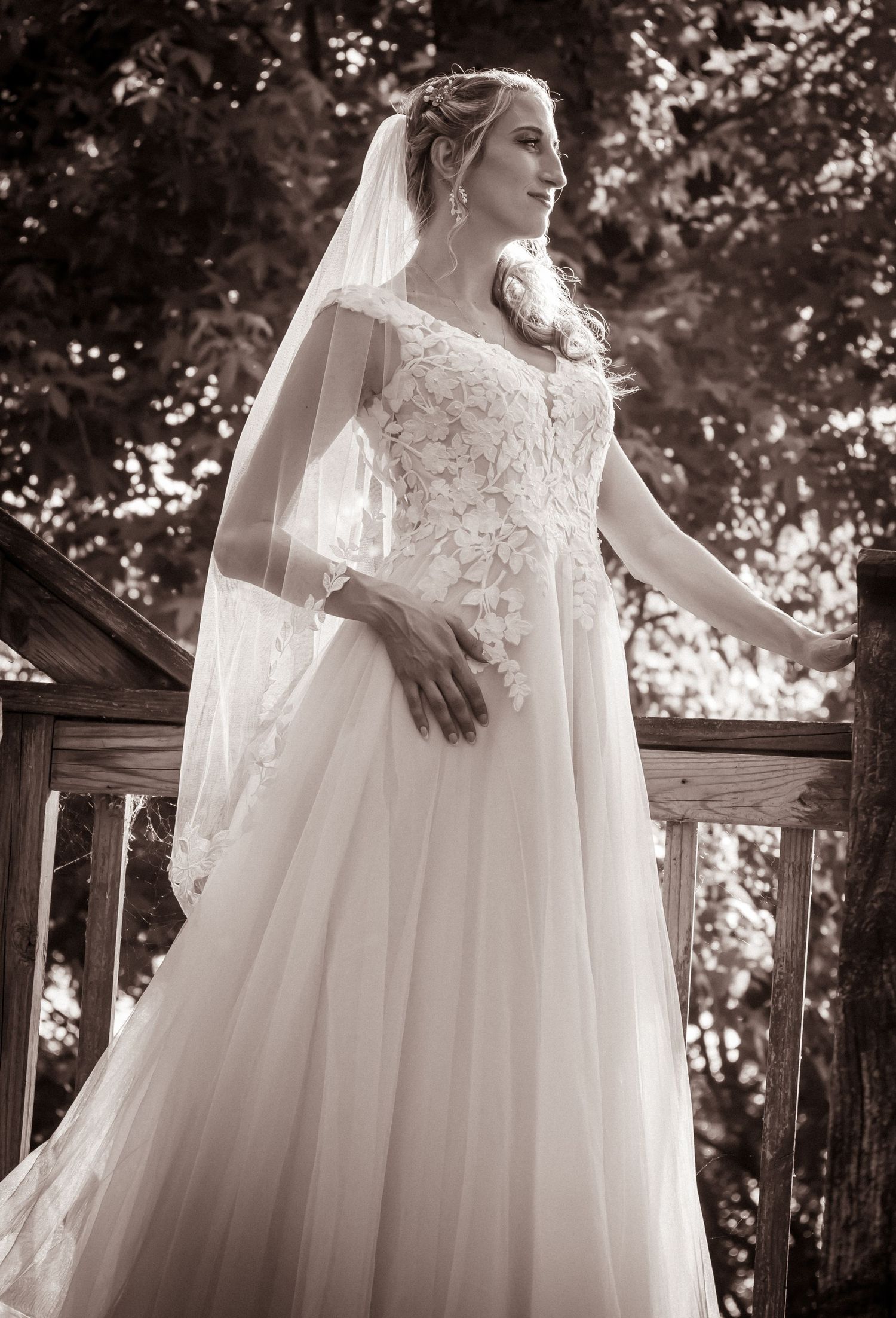 A wedding dress with lace details and flowing veil photographed outdoors.