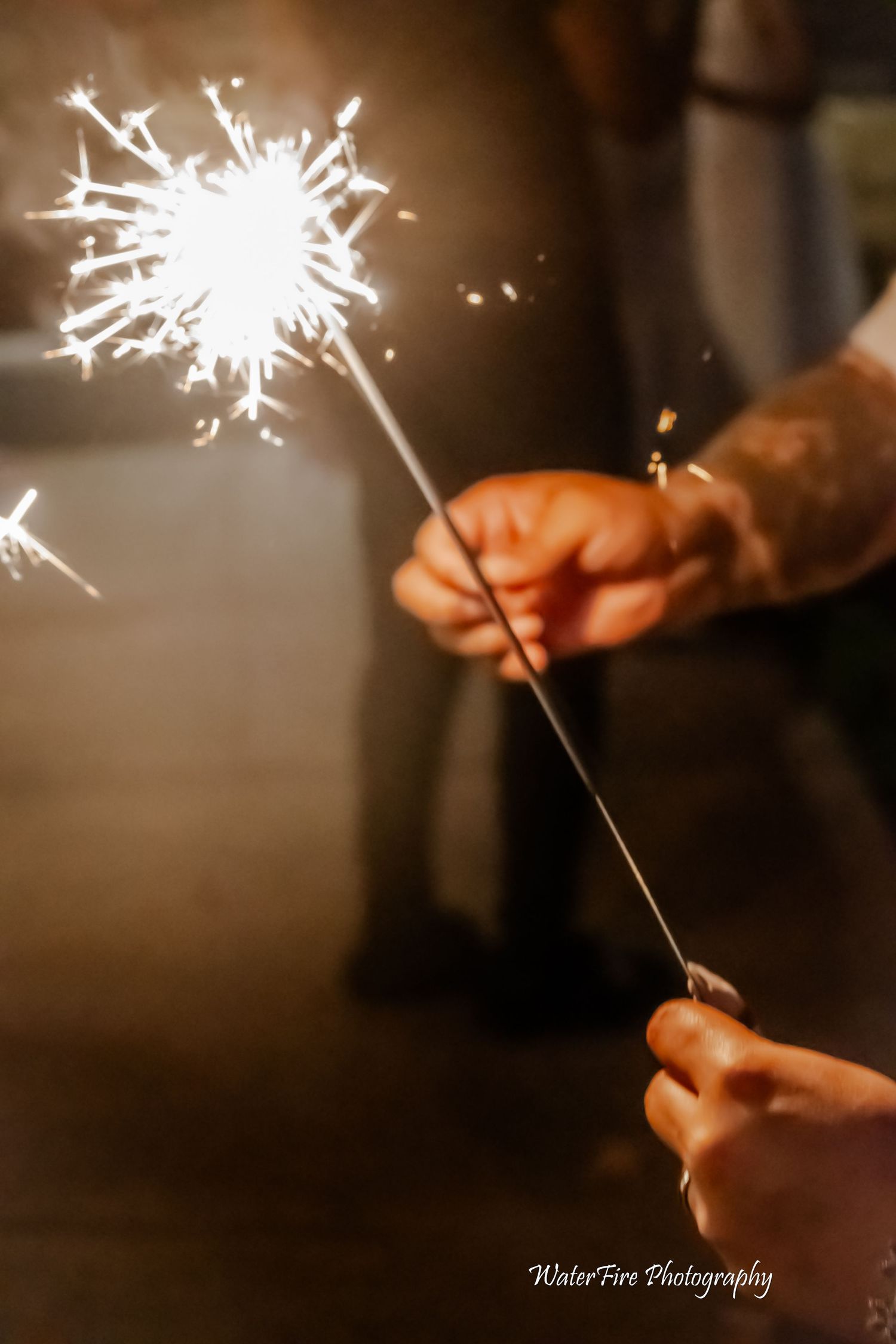 A glowing sparkler held during wedding celebrations creates magical light trails.
