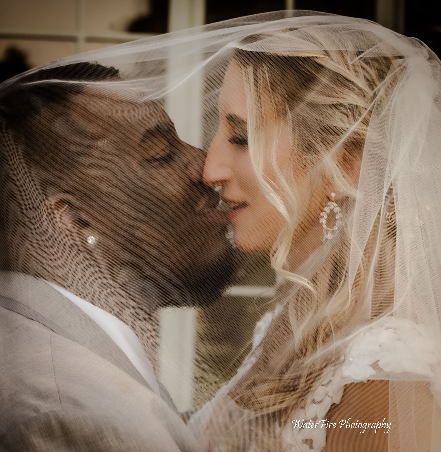 Close-up romantic wedding kiss with bride wearing white veil.