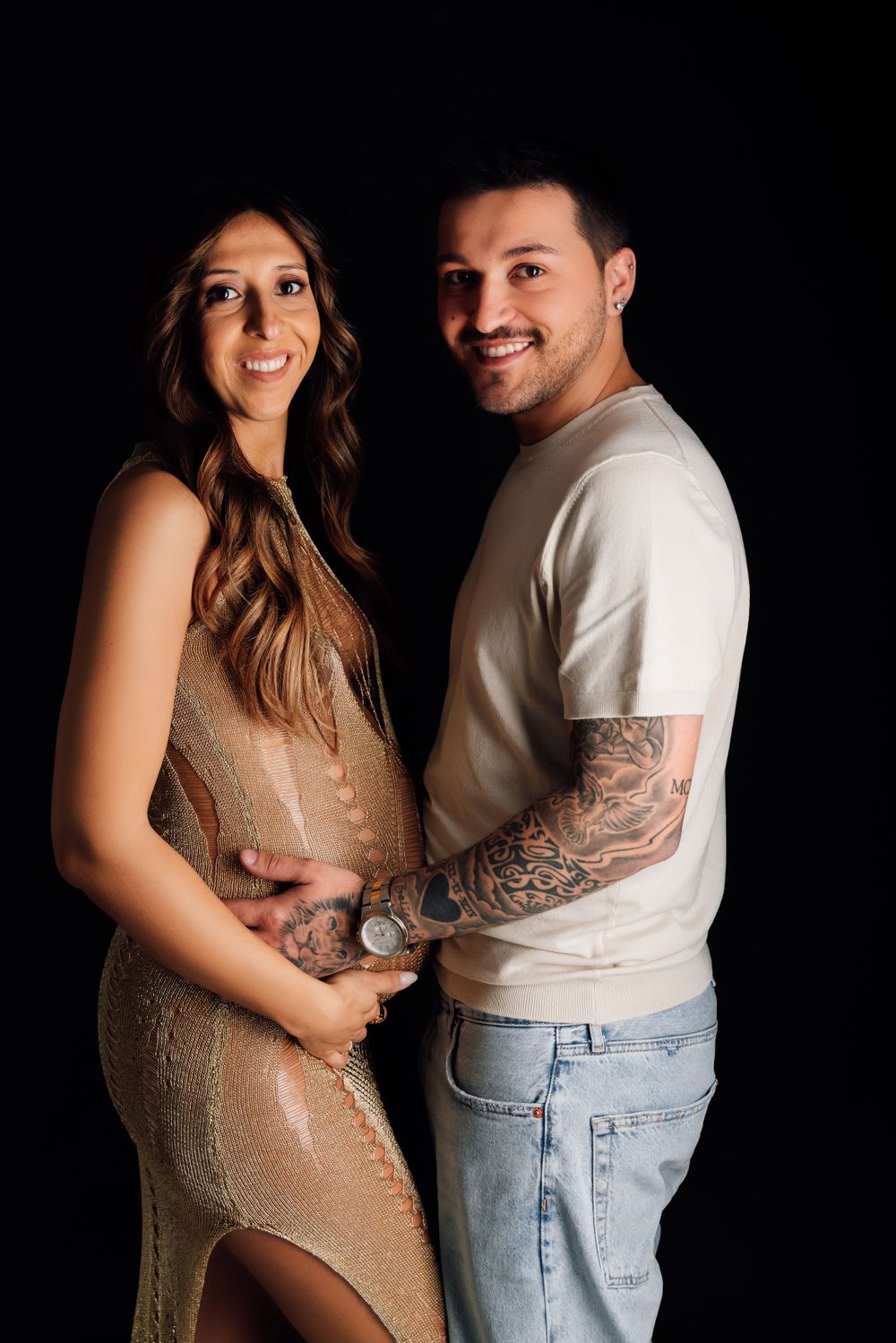Formal maternity portrait with couple in sparkly dress and casual white shirt.