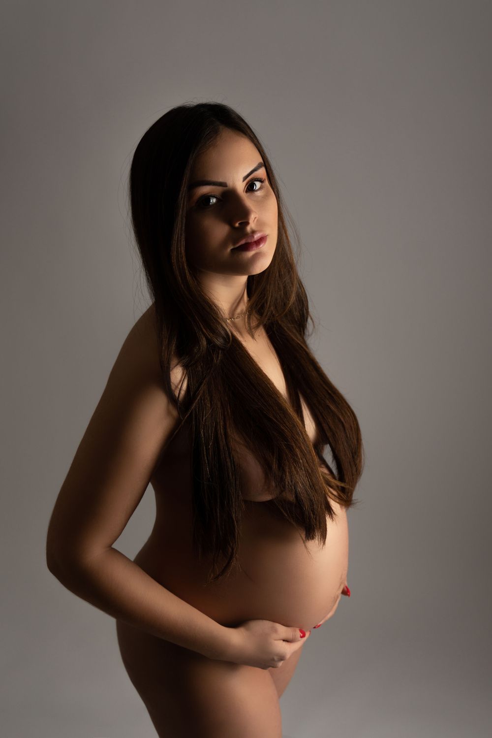 Dramatic studio portrait against dark background with artistic lighting.