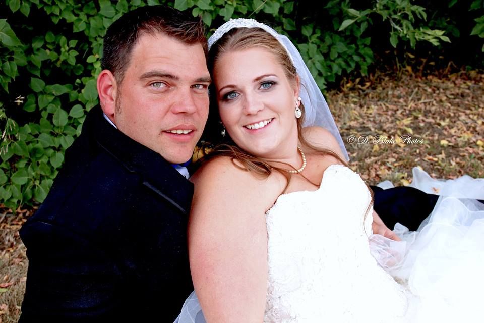 A wedding portrait in traditional dress against a green background.