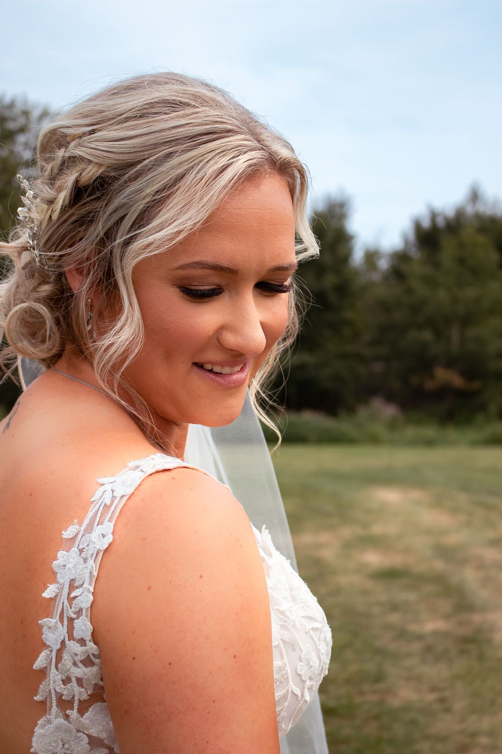 A close-up bridal portrait showing lace dress detail and elegant hairstyle.