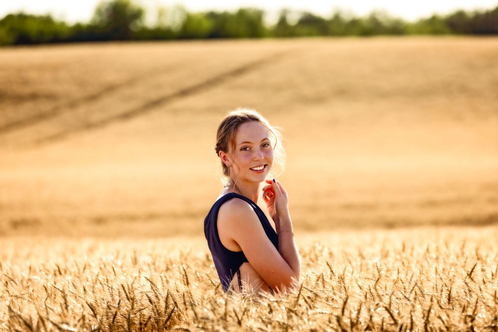 Golden wheat field at sunset creates warm backdrop for portrait.
