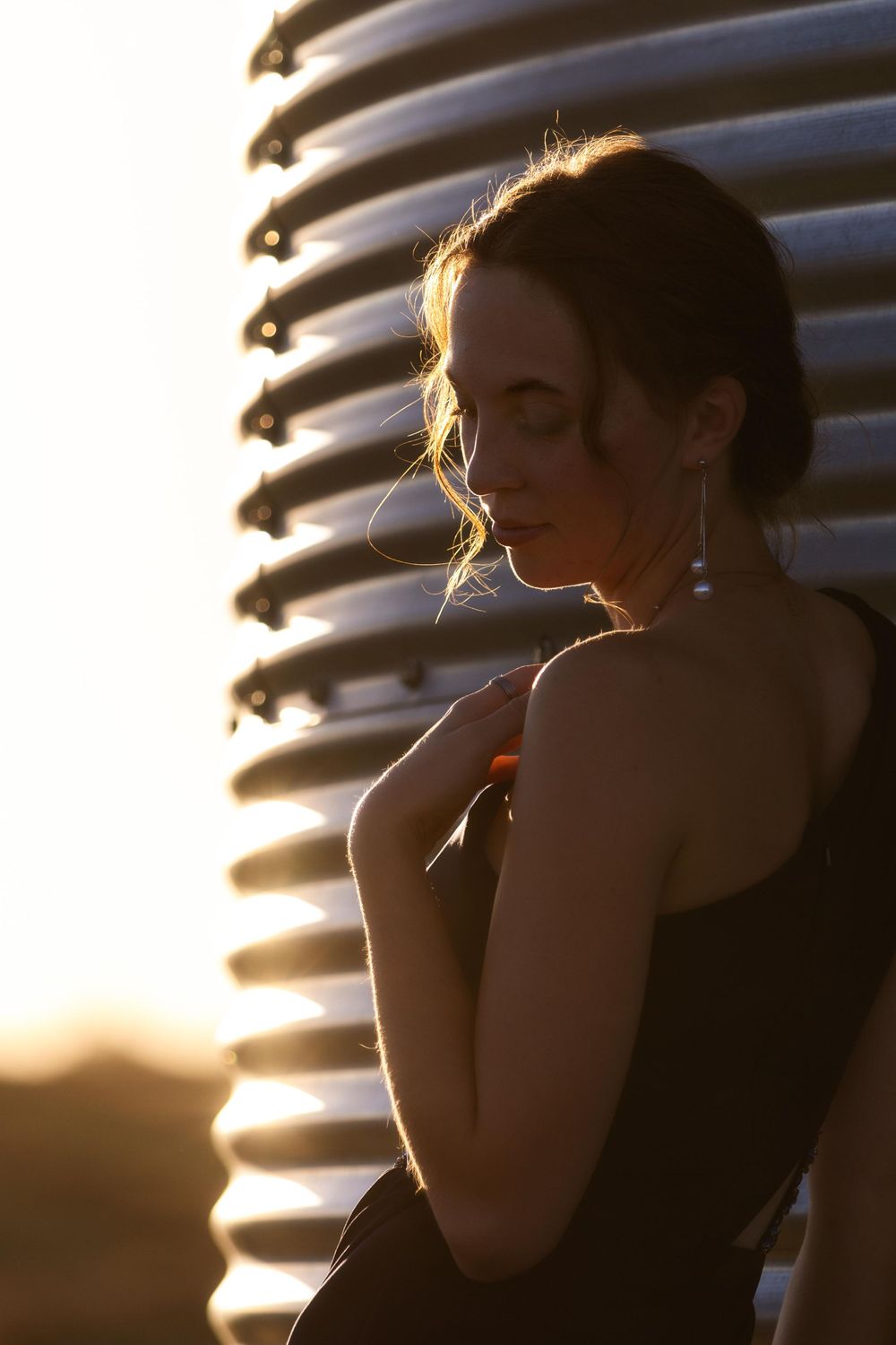 Silhouette against metal grain silo during golden hour sunset.