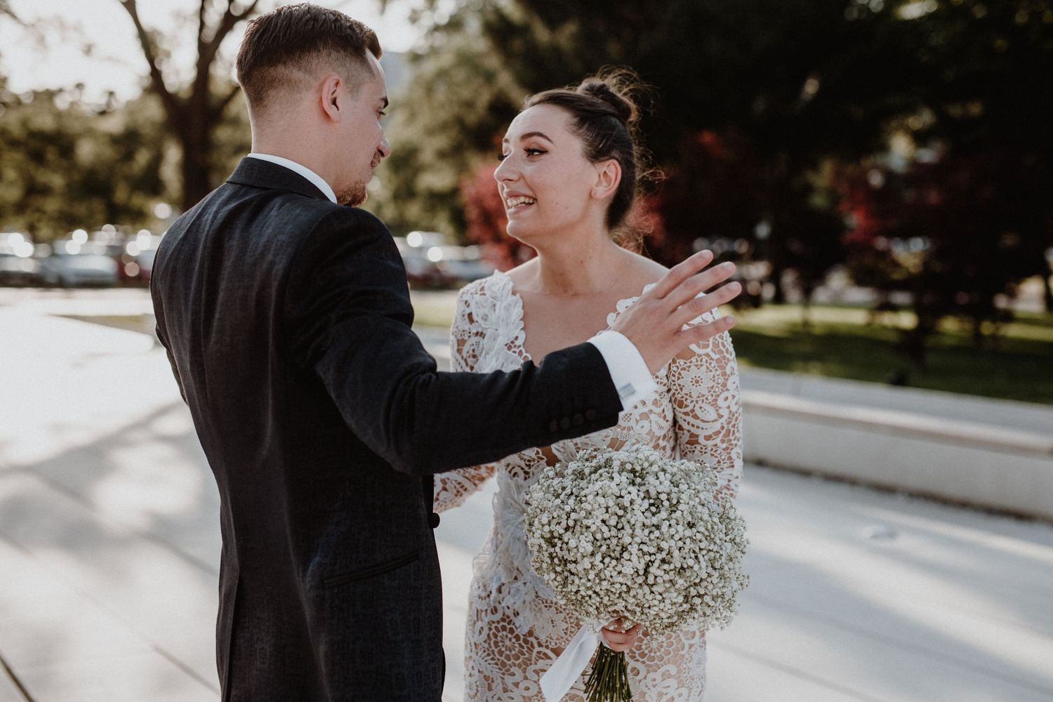 A couple shares a romantic moment outdoors in formal wedding attire.