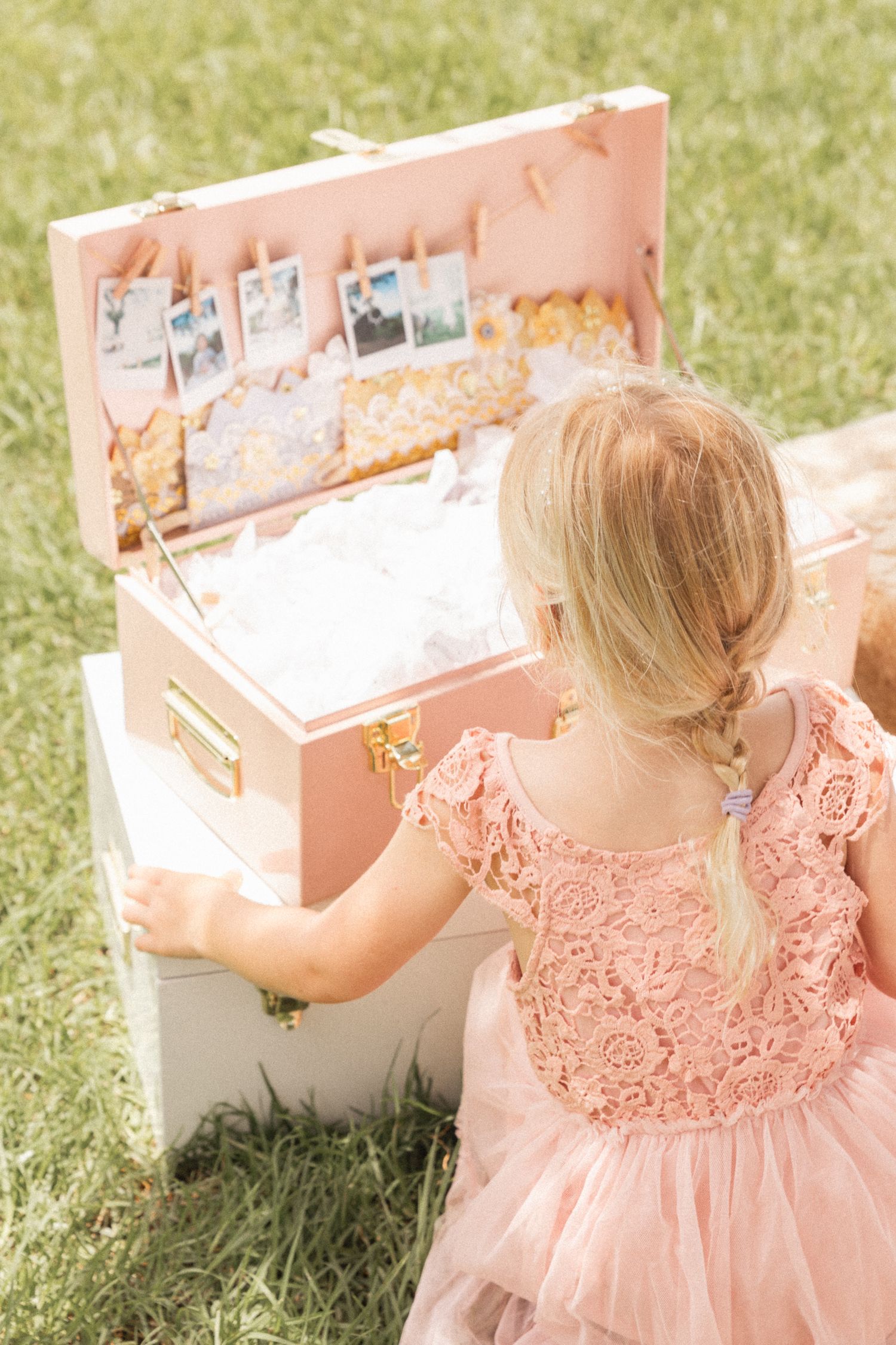 Pink lace dress detail against rustic wooden tea party setup in a grassy field.