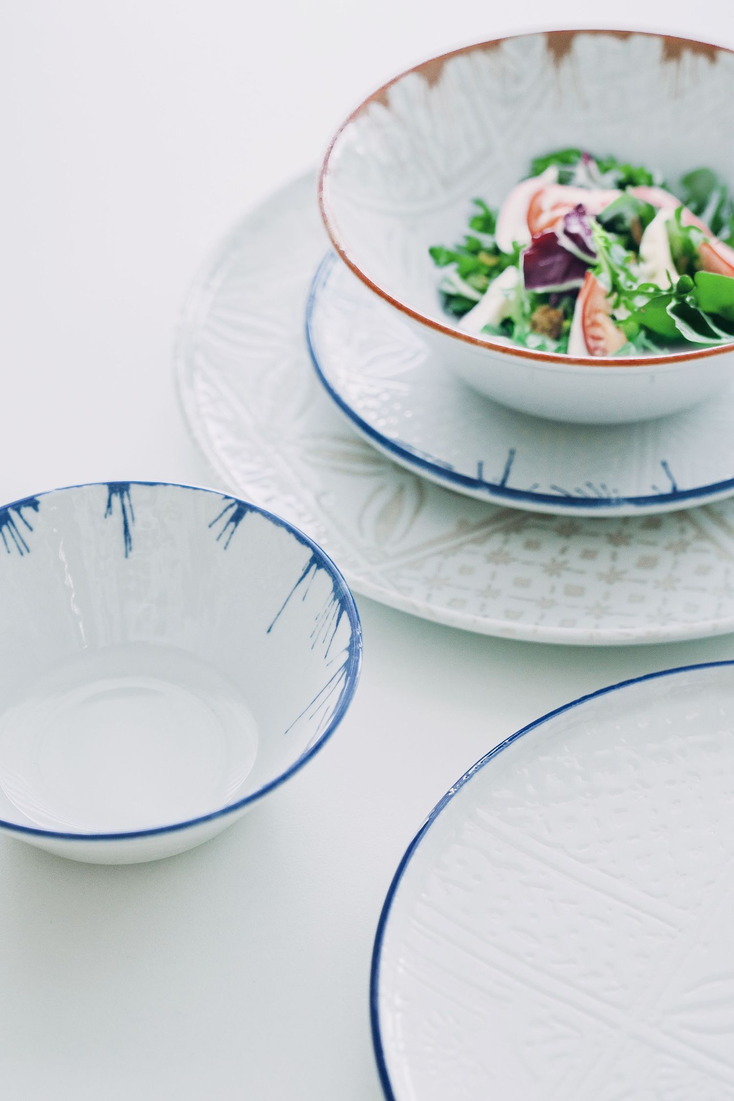 Digitally printed porcelain plates and bowls with mosaic patterns, arranged on a hard porcelain.