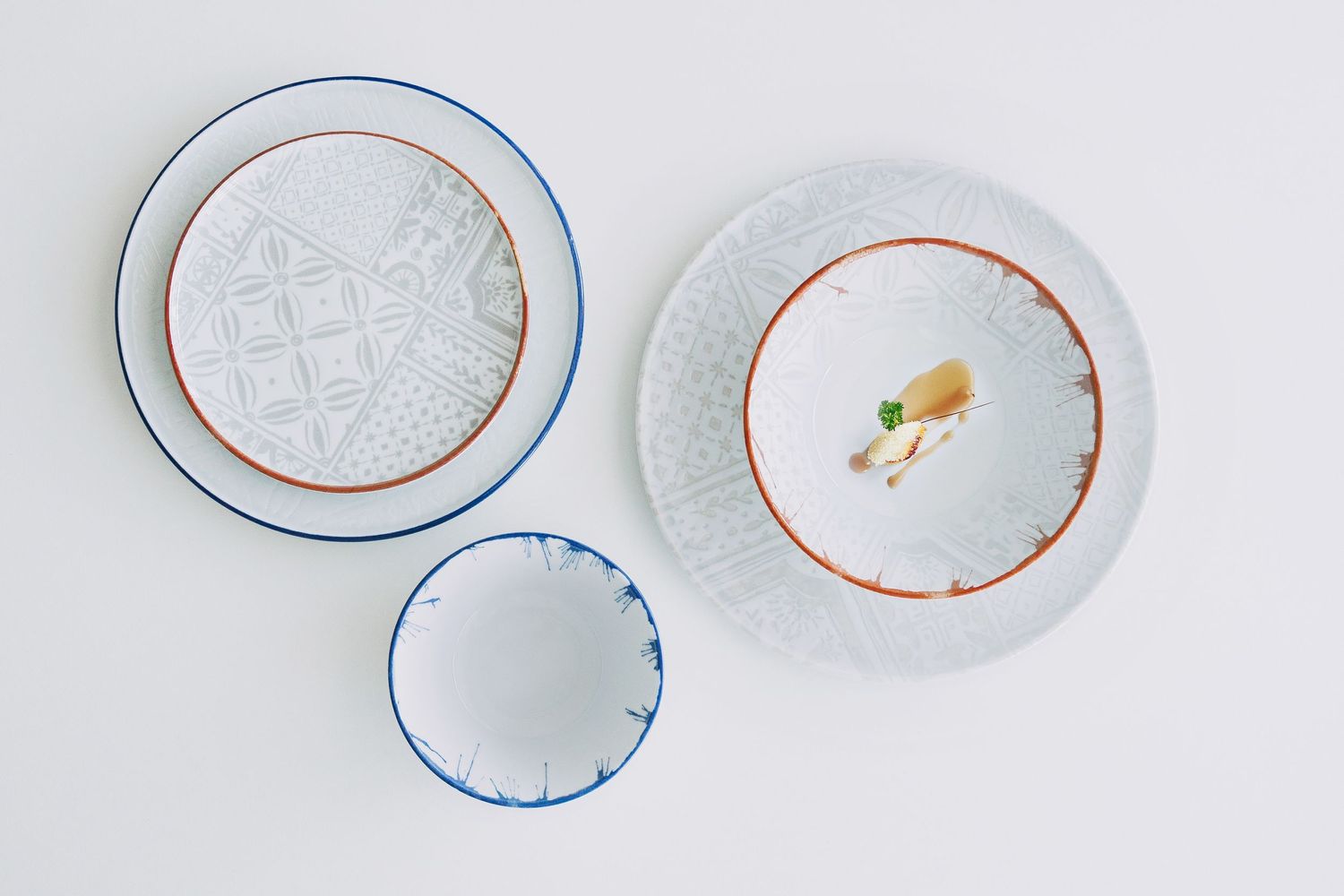 Digitally printed porcelain plates and bowls with mosaic patterns, arranged on a hard porcelain.