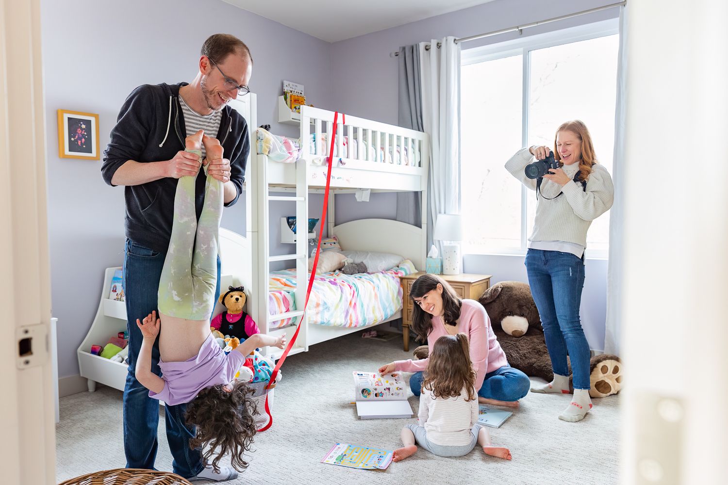 A playful family scene in a bedroom with bunk beds as parents and children interact.