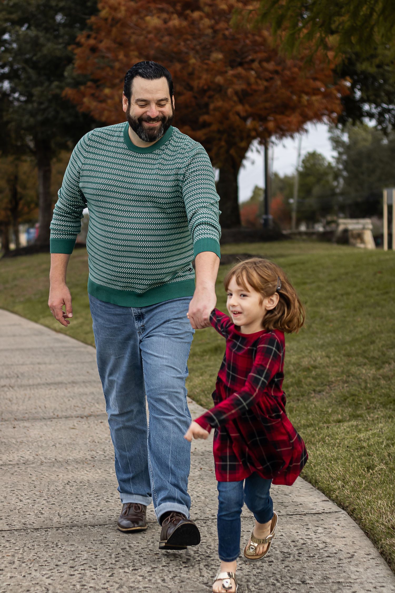 Parent and child walking and playing together on a sidewalk during autumn.