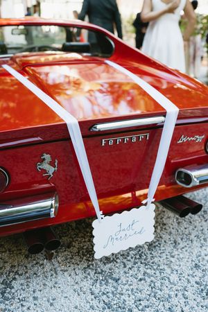 Red vintage Ferrari with white wedding ribbons parked on gravel.Best wedding photographer in Adelaide SA