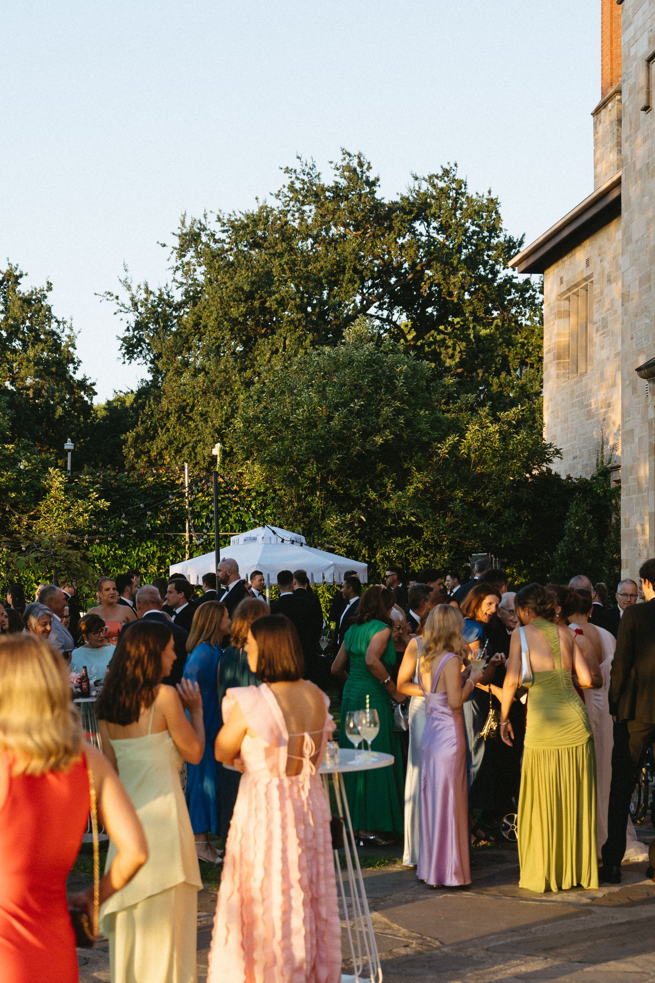 Colorfully dressed wedding guests gathered at an outdoor reception venue during golden hour. Best wedding photographer in Adelaide SA