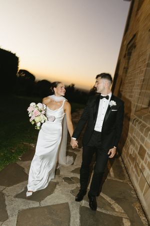 Wedding couple sharing a candid moment while walking along stone path at dusk. Best wedding photographer in Adelaide SA