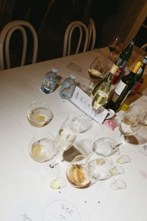Messy table with empty wine glasses, bottles, and water after a wine tasting event.