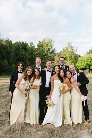Wedding party in cream dresses and black tuxedos posing together in an outdoor field setting. Best wedding photographer in Adelaide SA