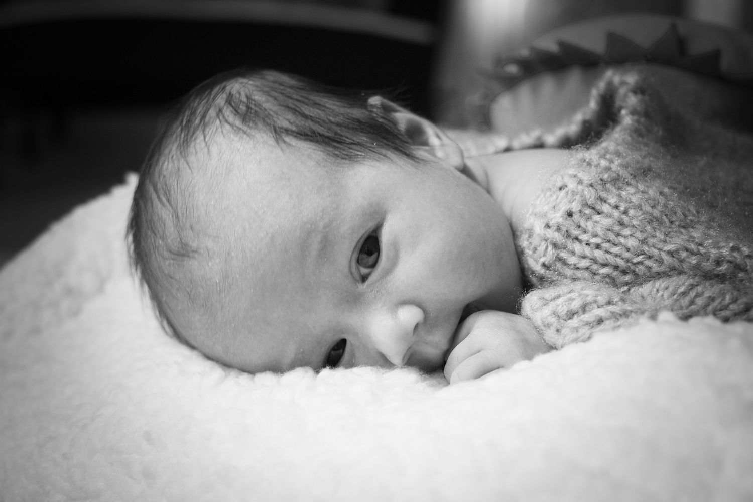 Close up of infant resting on soft knitted blanket in black and white.