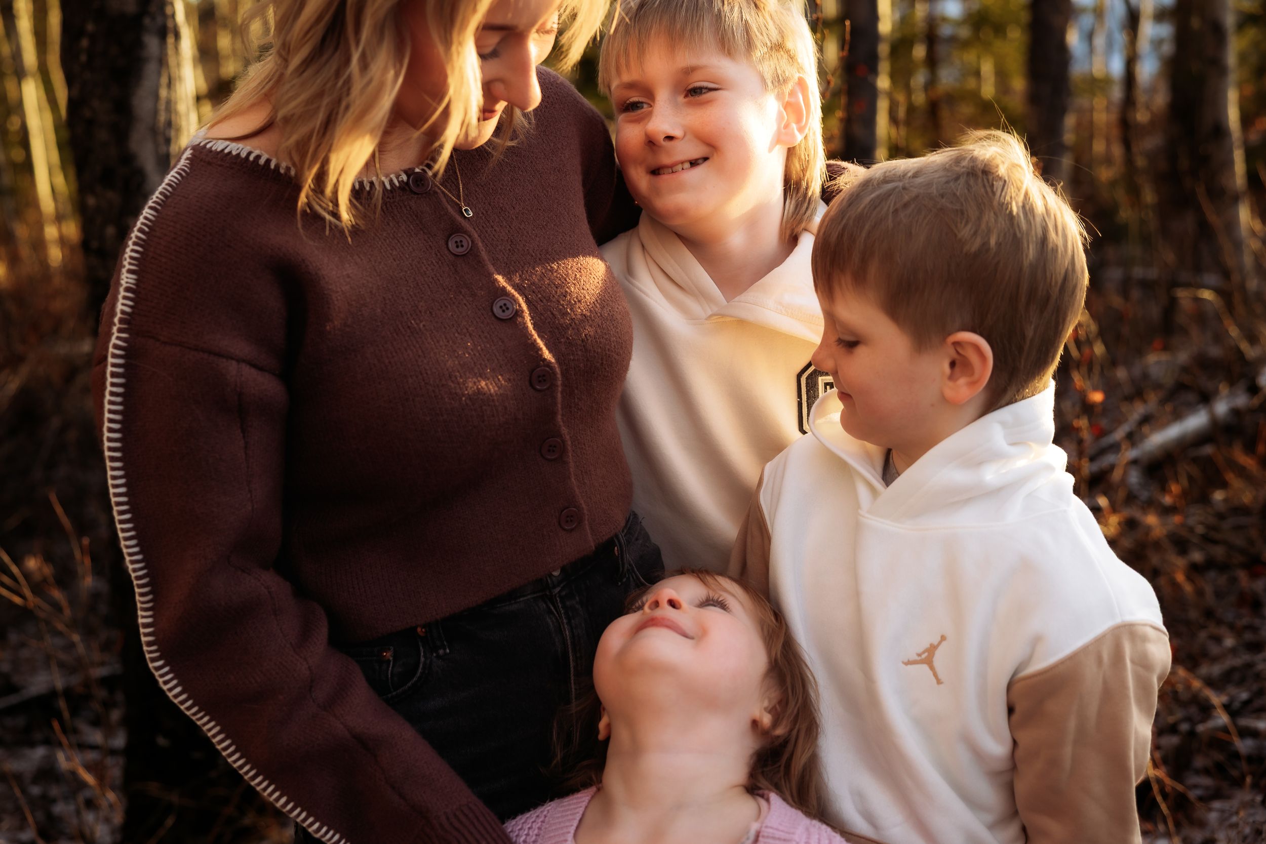 A loving family shares tender moments together while sitting outdoors in an autumn forest setting.