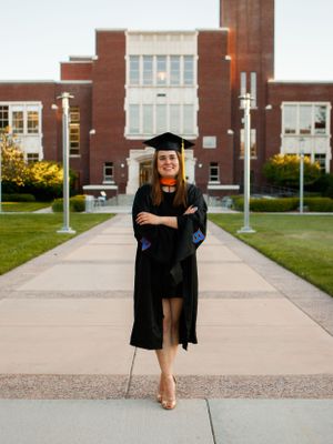a grad walking towards the camera in front of an old building
