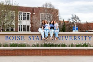 four grads sat on top of a Boise State University sign