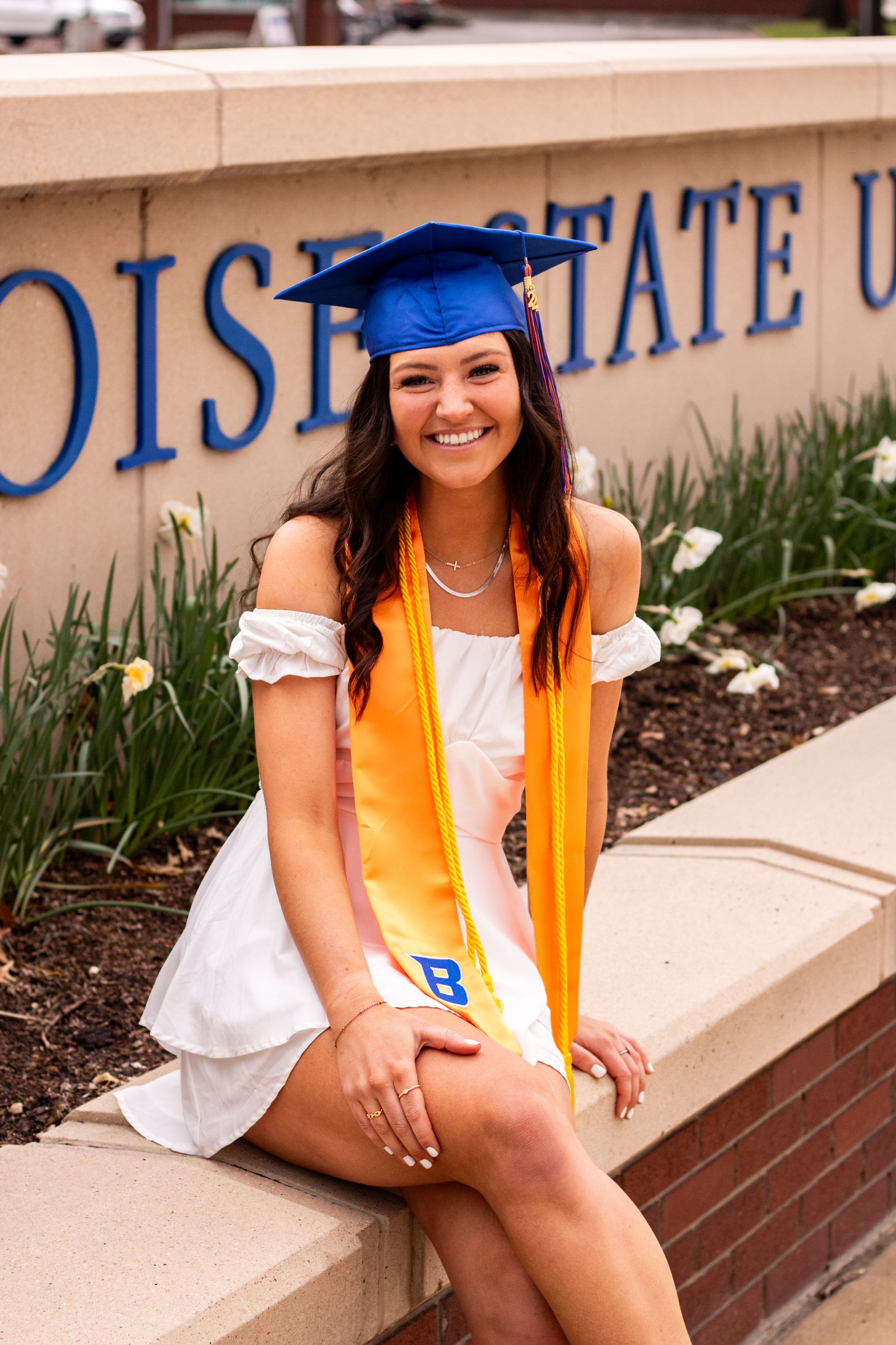 a grad posing in front of flowers