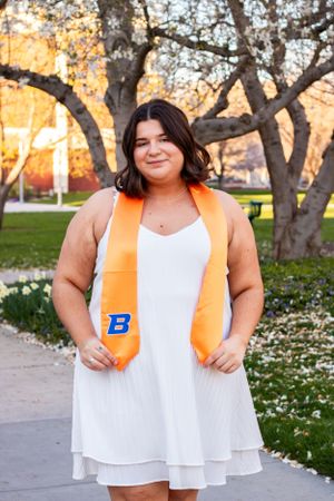 a grad posing in front of some flowers