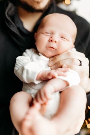 Close-up series of a newborn baby in white clothing against dark background.
