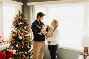 Family gathering around decorated Christmas tree in bright living room.